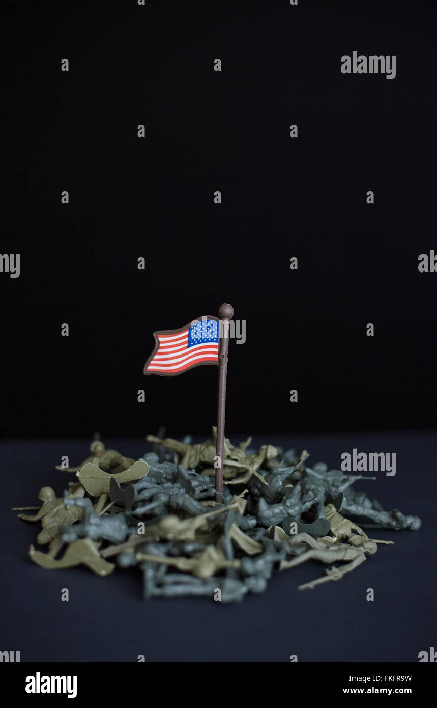Scattered, fallen toy soldiers around a plastic US flag. Stock Photo