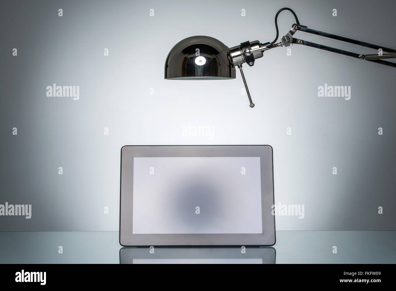 lighting up tablet touchpad note with desk lamp on round studio lighting Stock Photo