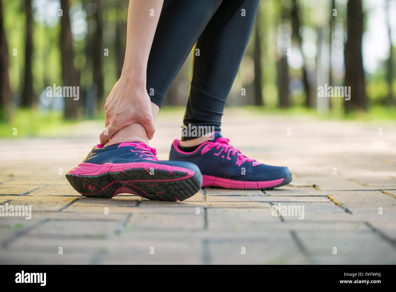 woman runner hold twisted ankle Pain ,Human Leg Cramp Stock Photo