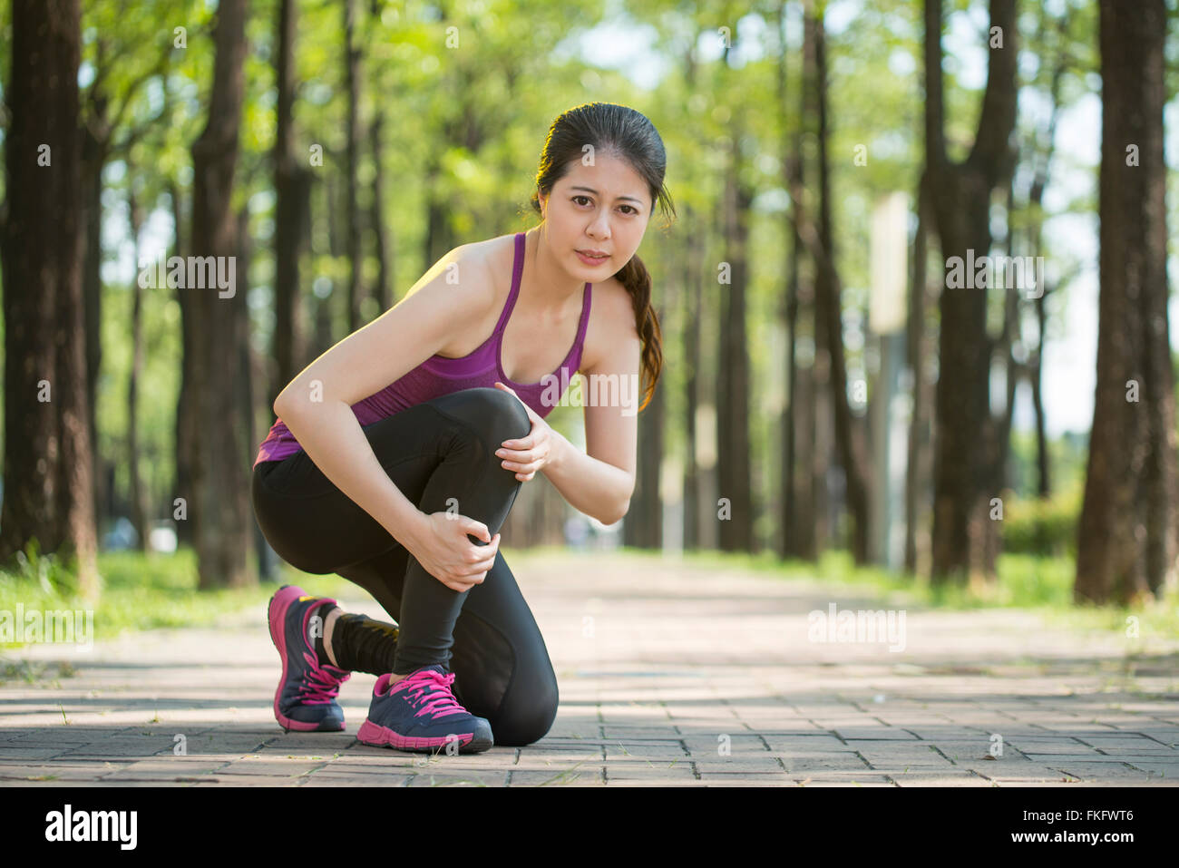 Asian woman runner hold Knee Pain ,Human Leg, jogging Stock Photo