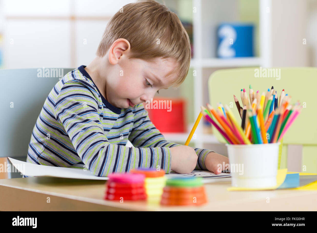 Preschool child use pencils and paints for homework received from kindergarten Stock Photo