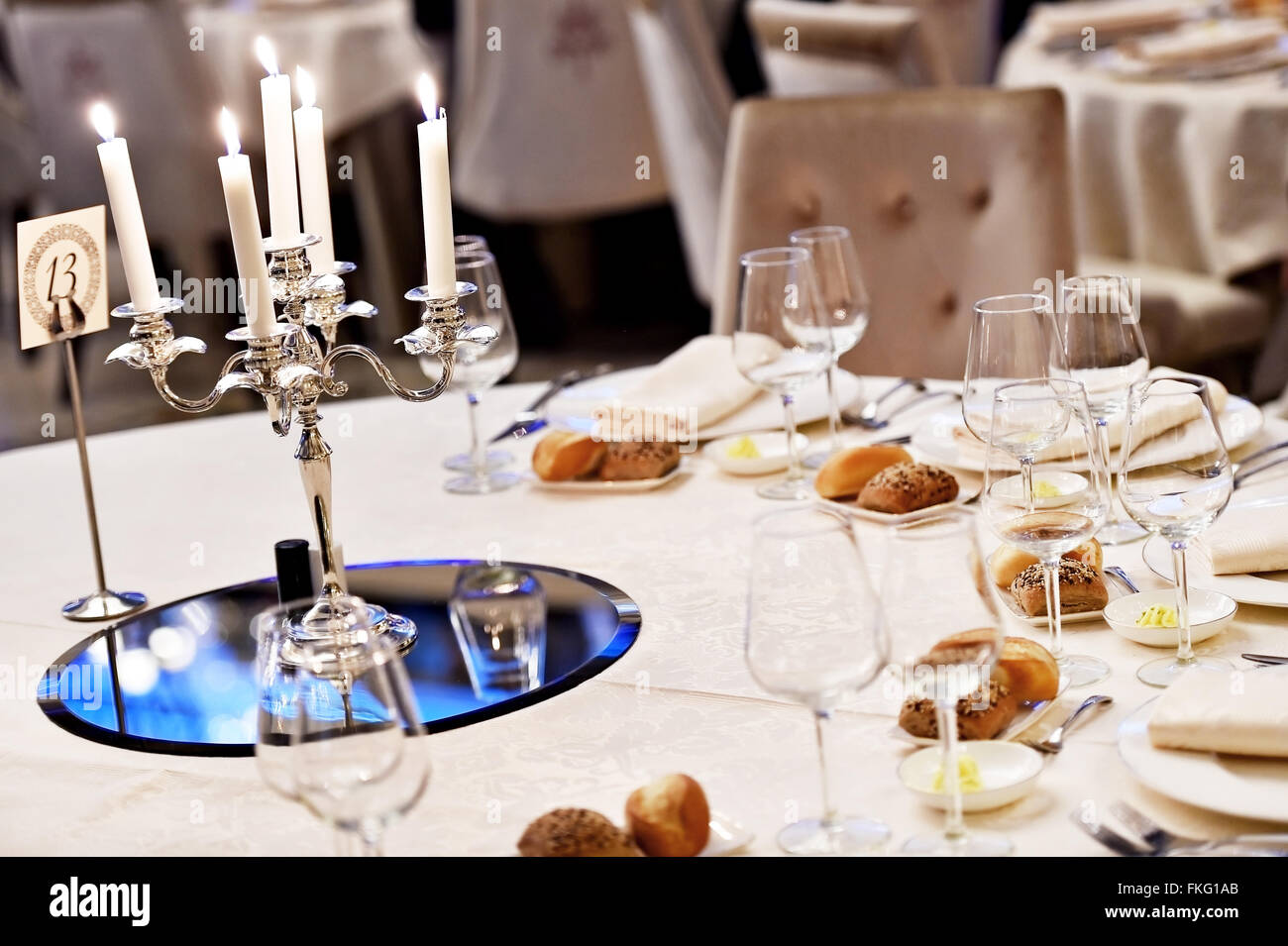 Candles burning in a chandelier on elegant dinner table Stock Photo