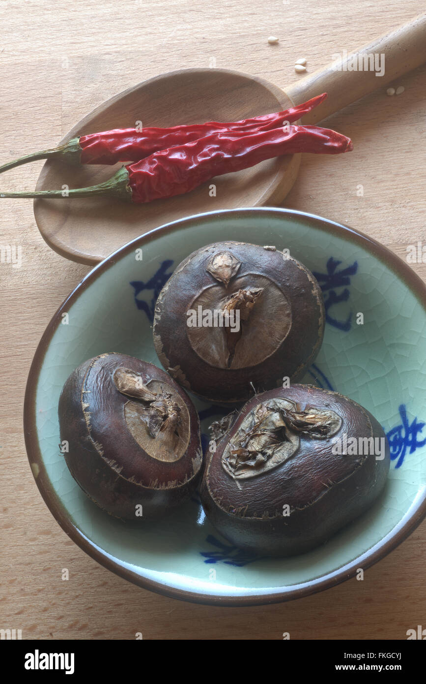 Wasserkastanien in Keramikschale mit chinesischer Schrift, Water chestnuts in a bowl with Chinese symbols Stock Photo