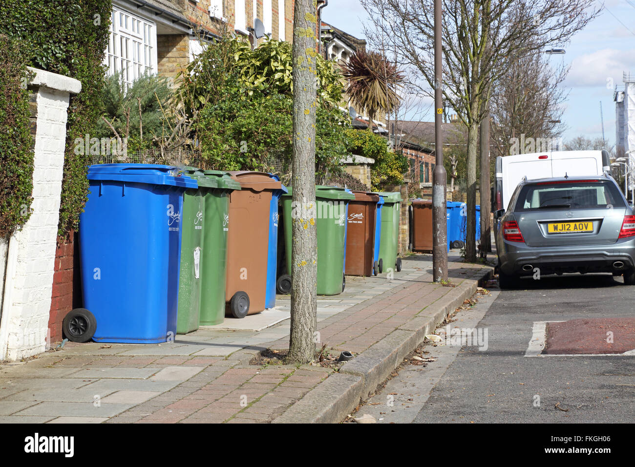 Household refuse recycling bins take up most of the pavement space on a