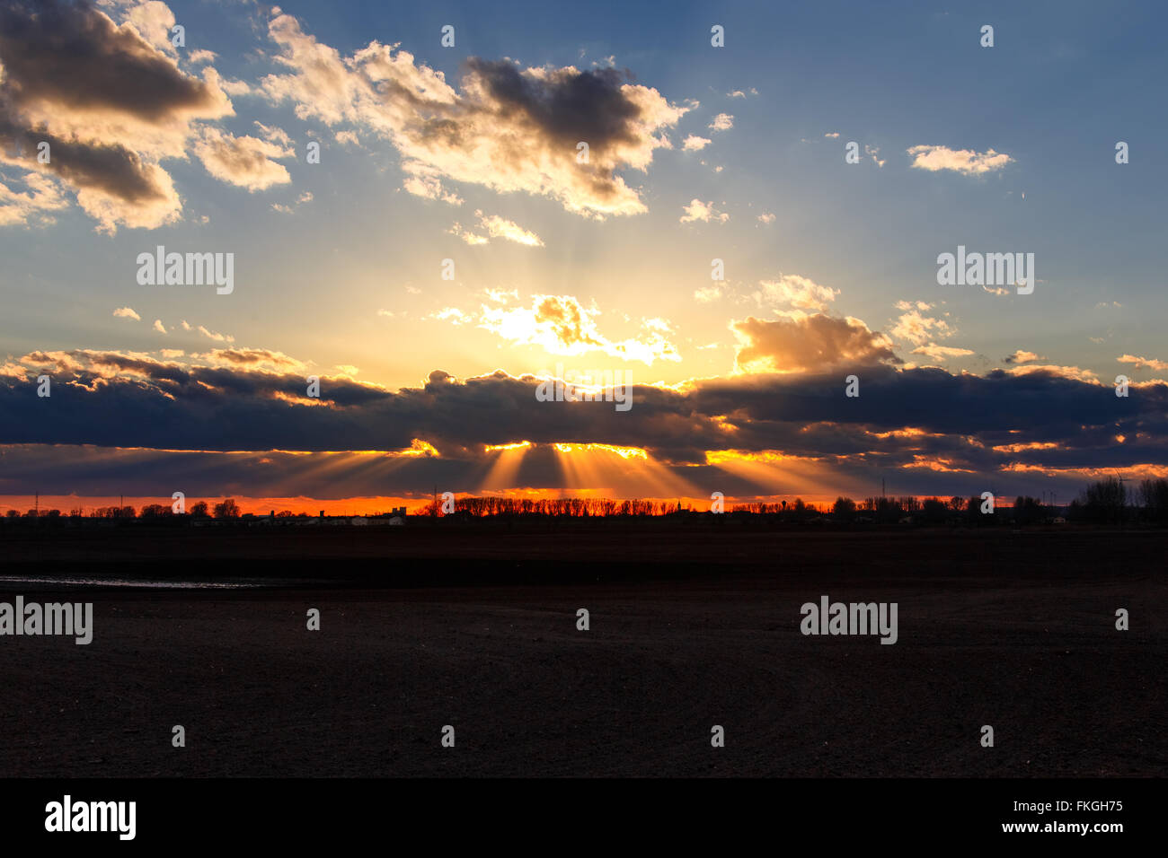 Golden sun rays behind clouds sunset with field Stock Photo - Alamy