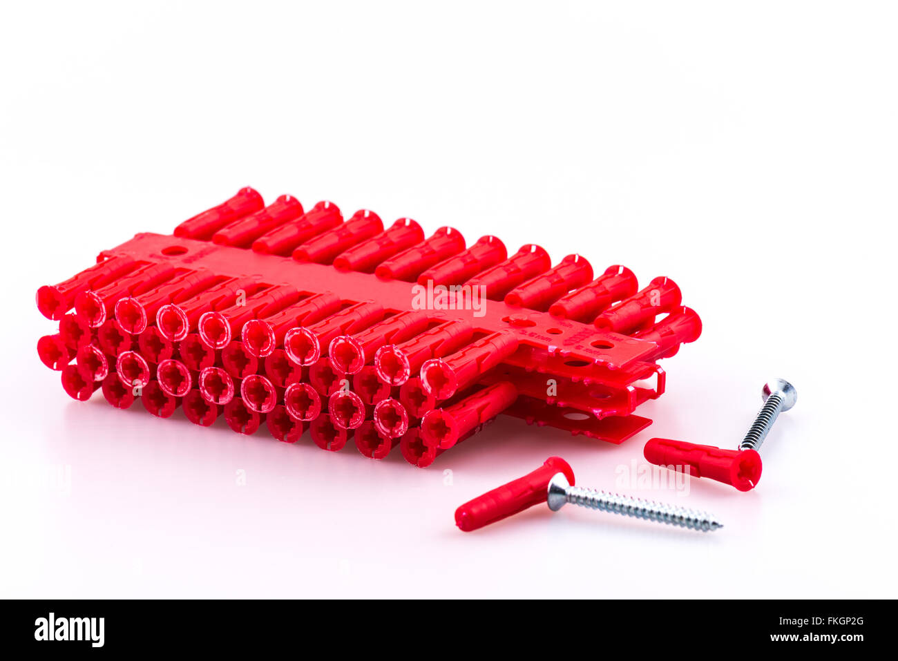 Block of red rawl wall plugs and two screws on white background Stock