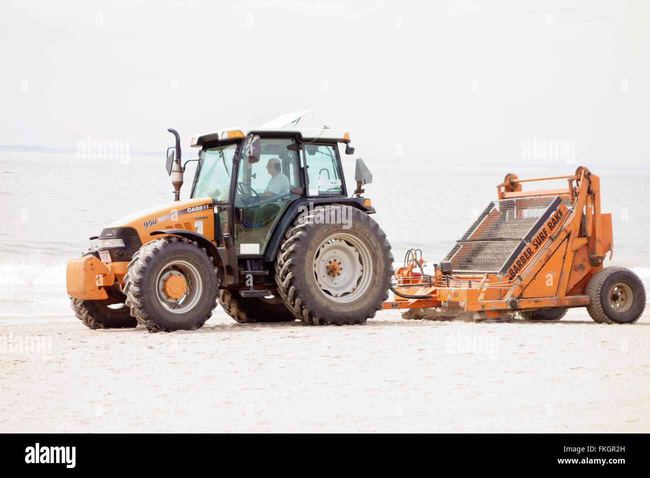 Man driving a tractor towing a beach cleaning machine on Coney Island ...