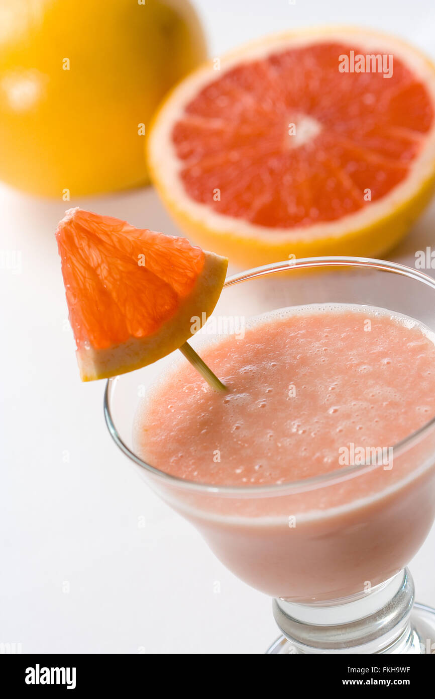 Healthy grapefruit smoothie in a glass with fresh grapefruit in the background. Stock Photo
