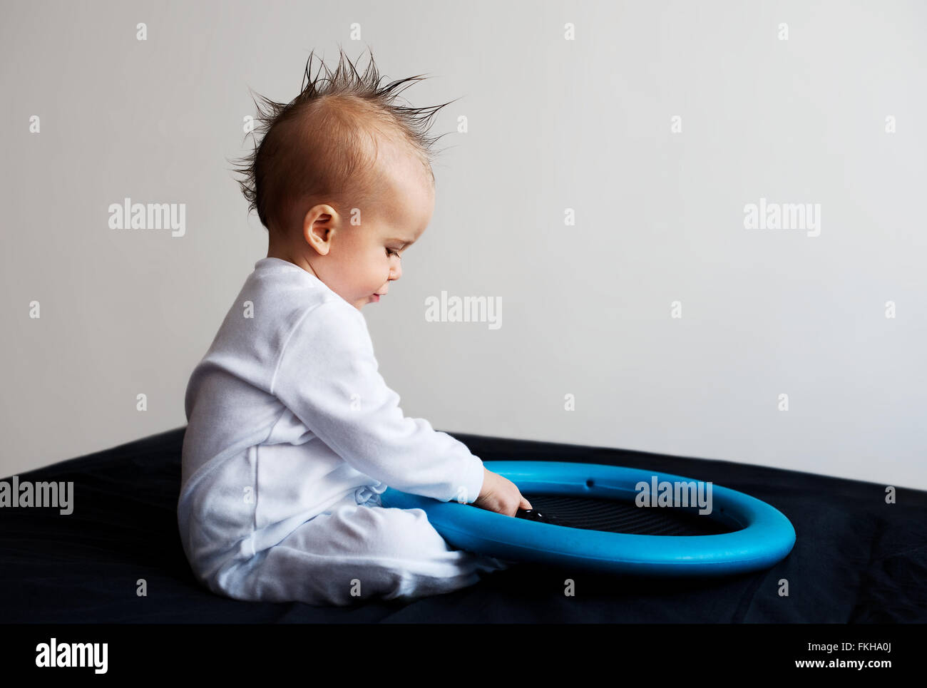 Baby with mohawk sitting and playing Stock Photo