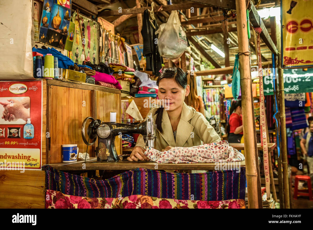 Young asian woman works at an old sewing machine at a local market in Yangon Stock Photo
