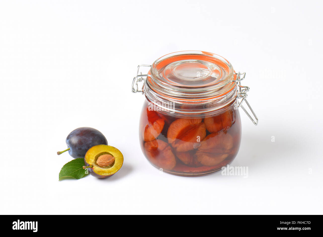 fresh plums and jar of preserved plums on white background Stock Photo