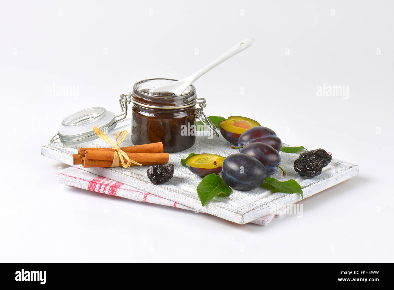 plum jam, cinnamon, fresh and dried plums on wooden cutting board Stock Photo