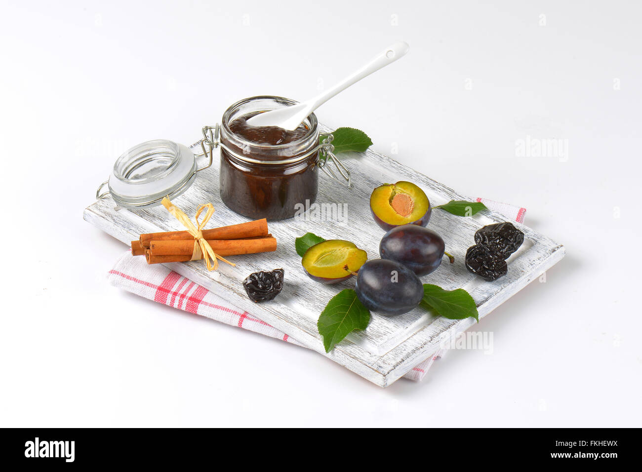 plum jam, cinnamon, fresh and dried plums on wooden cutting board Stock Photo