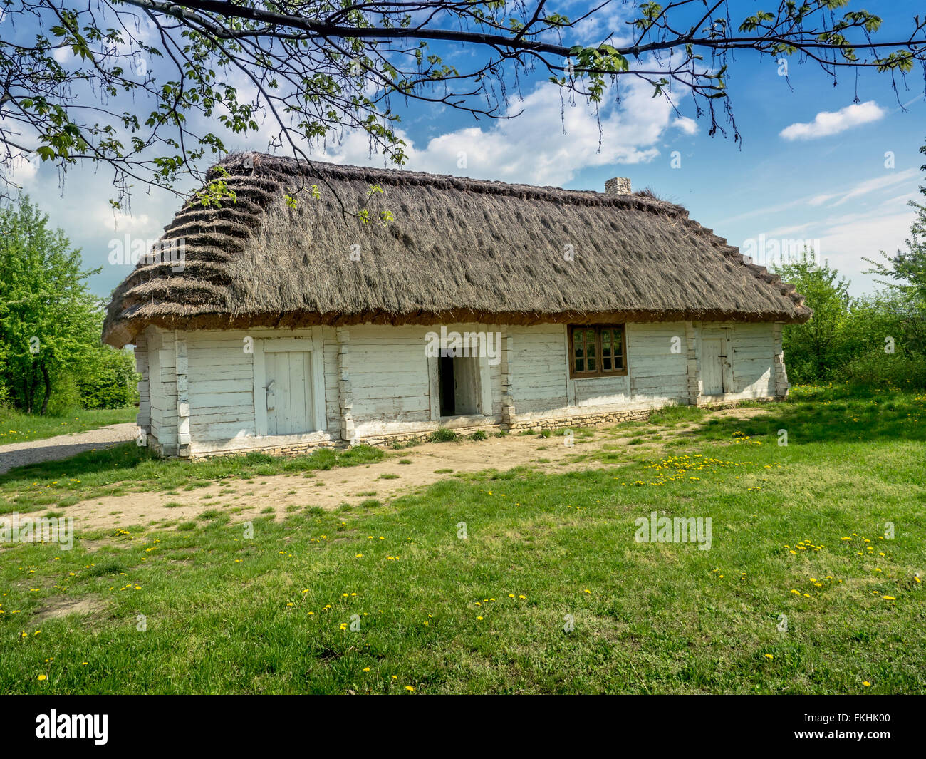 Old style thatched wooden cottage with white walls Stock Photo