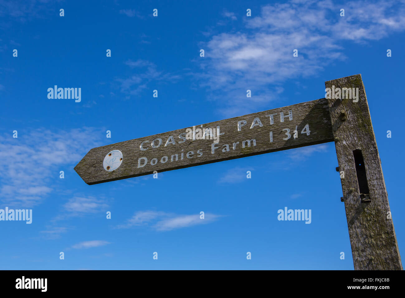 Sign for Doonies Farm and the Coastal Path at Aberdeen, Scotland, UK, with a vessel leaving harbour Stock Photo