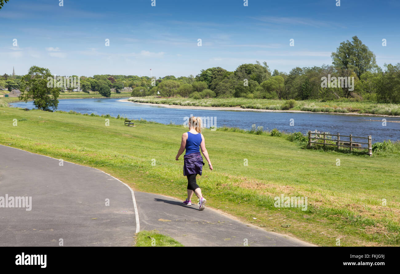Young woman walking beside the River Dee in the city of Aberdeen in Scotland, UK. Stock Photo