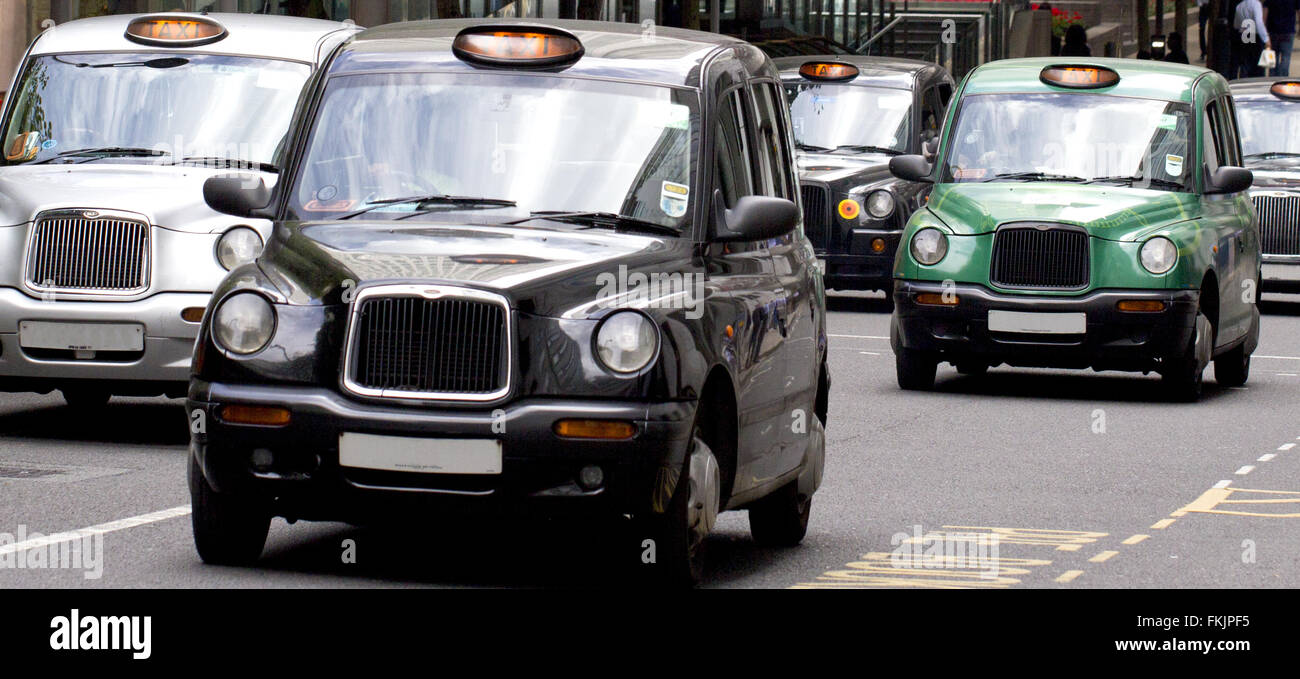 Five iconic, famous London black cab taxis travelling through Canary Wharf Stock Photo