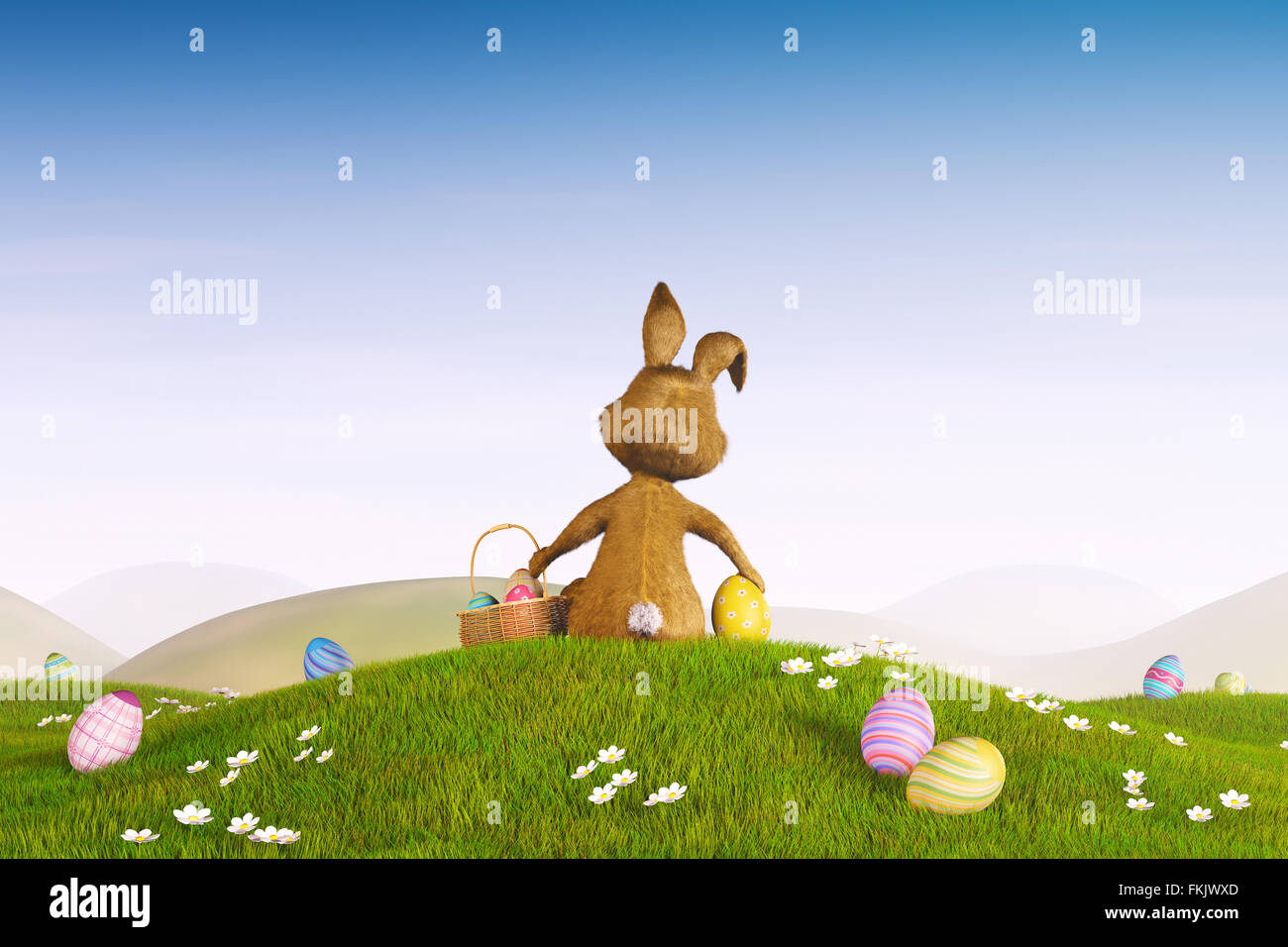 A cute Easter bunny sitting on a hill surrounded by easter eggs. Stock Photo