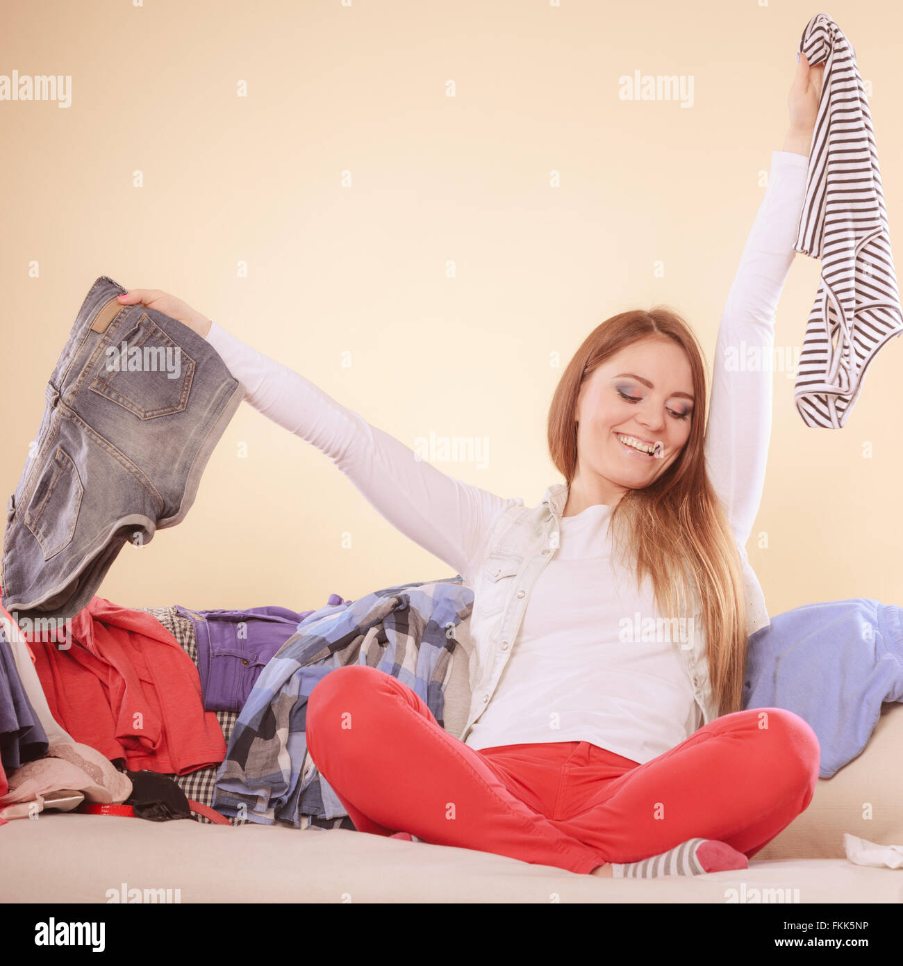 Happy Woman Sitting On Sofa Couch In Messy Living Room Holding