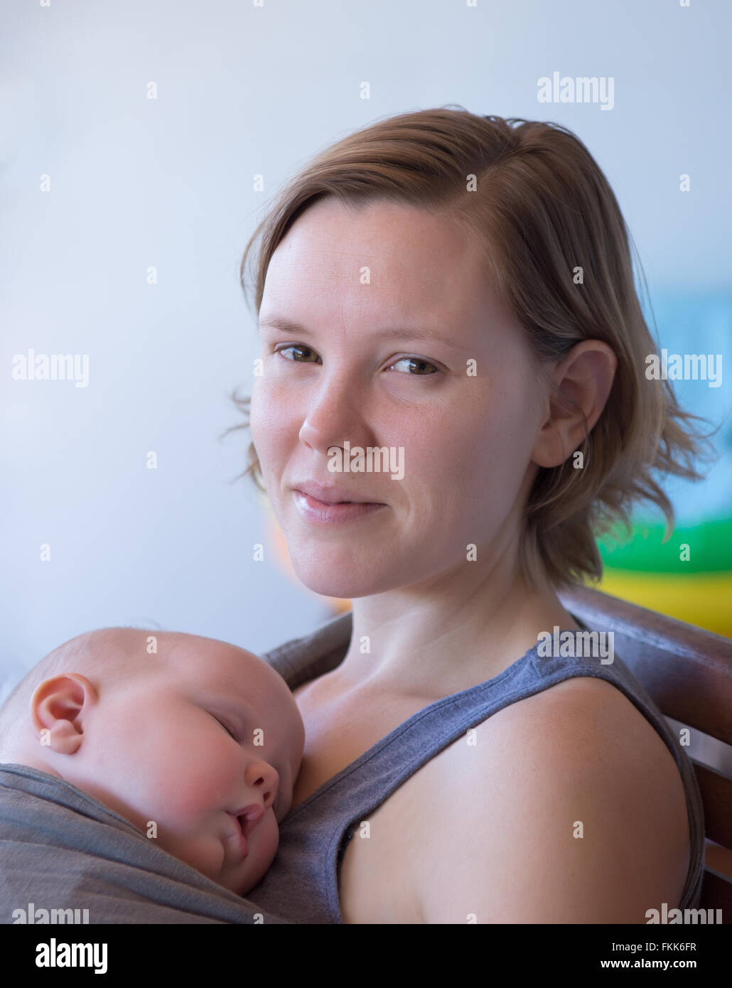 Mother holding sleeping baby held by baby carrier wrap Stock Photo