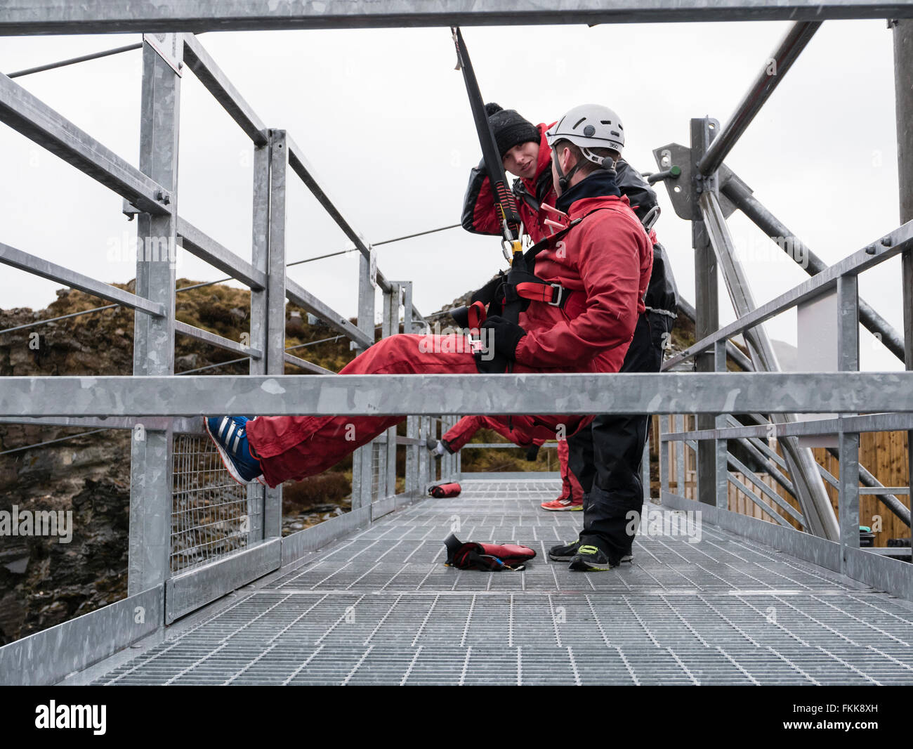 Man having safety checks on platform at start of zip wire ride at ZipWorld Titan in Snowdonia. Blaenau Ffestiniog North Wales UK Stock Photo