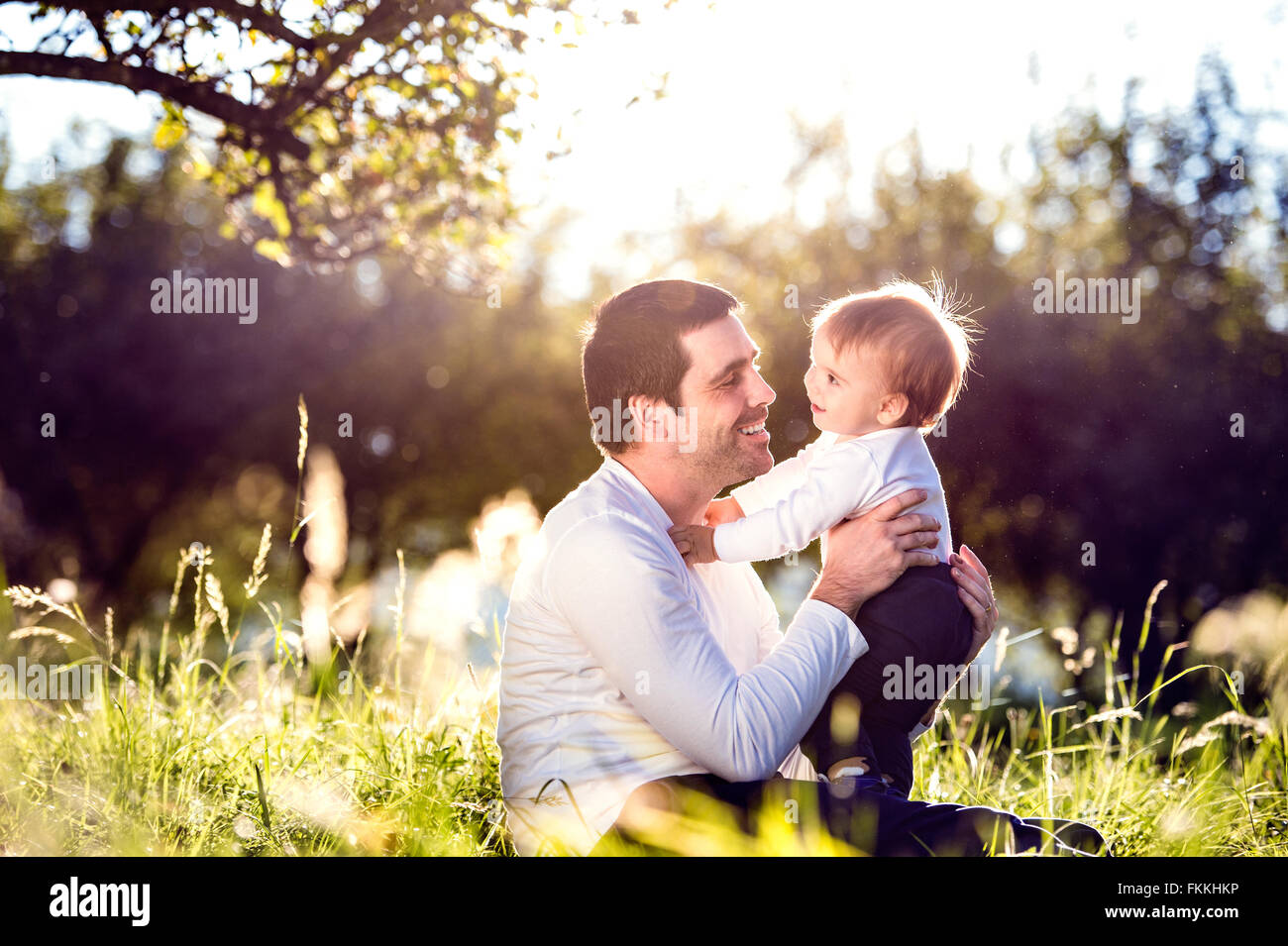 Father holding his little son, sitting on the grass Stock Photo - Alamy