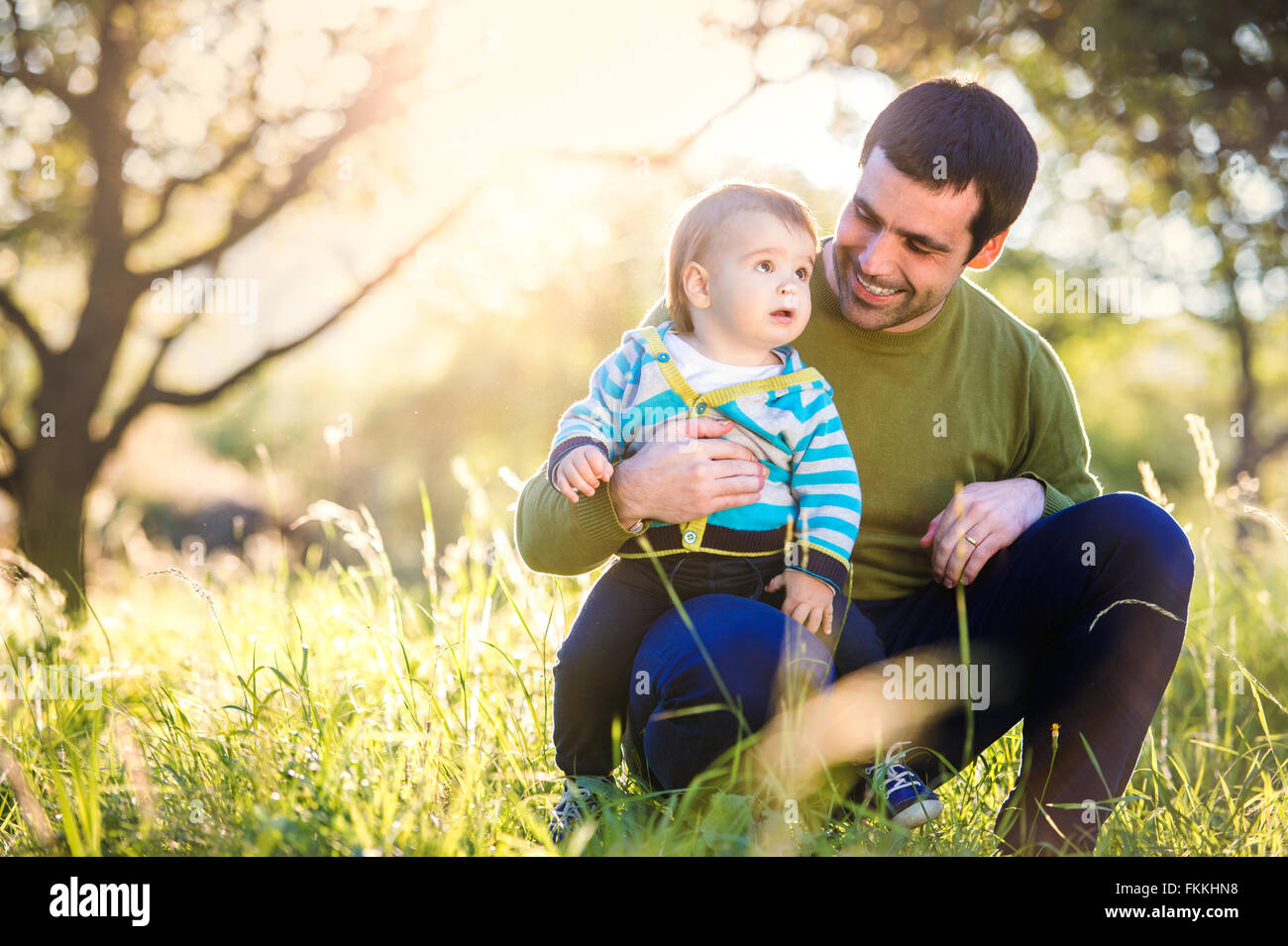 Father holding his little son, sitting on the grass Stock Photo - Alamy