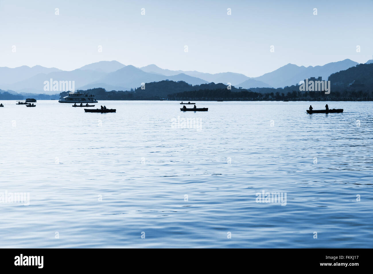 West Lake, panorama with local ordinary people in floating boats, Hangzhou city, China. Blue toned monochrome photo Stock Photo