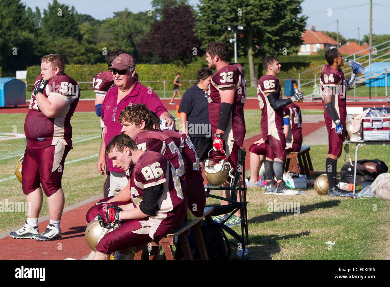 On a hot sunny day American football players and coach on the sideline Stock Photo