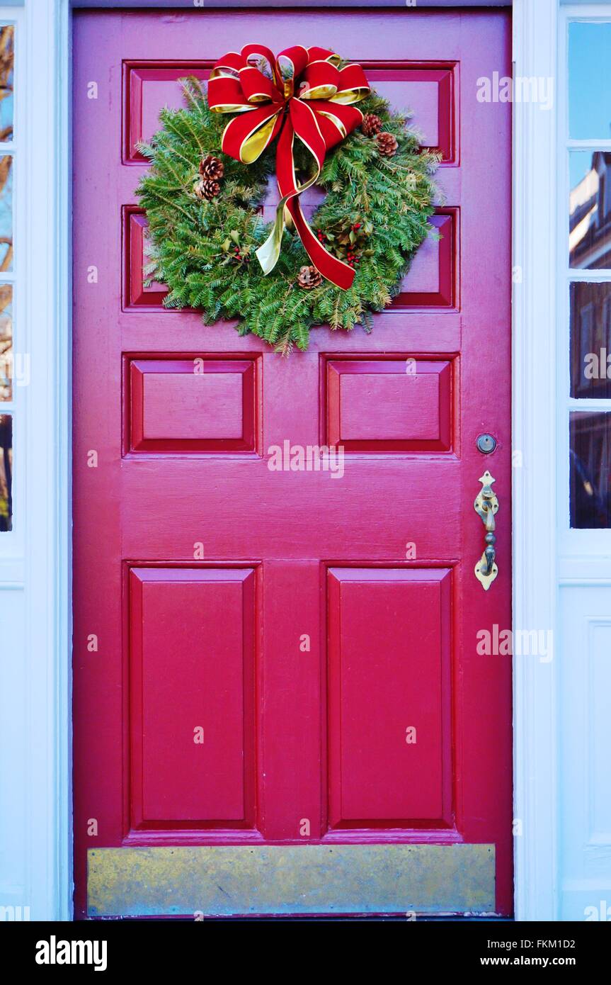 Christmas holiday pine wreath with pinecones and red bow on a red door ...
