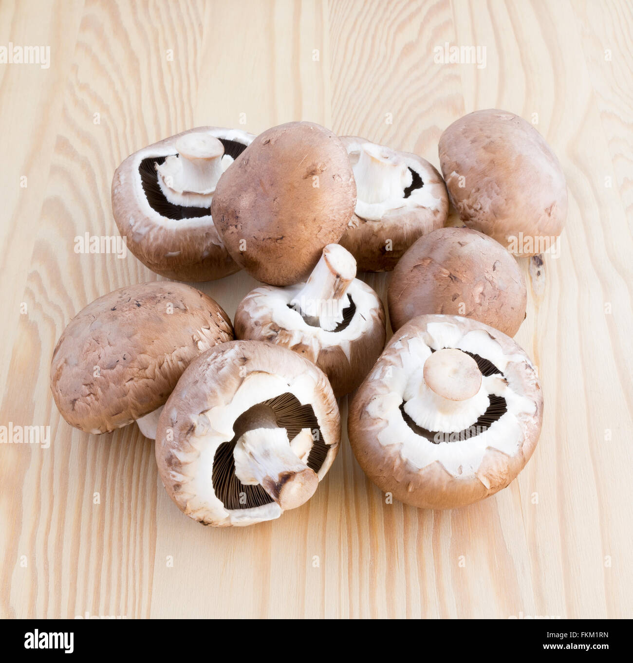 Many chestnut mushrooms on a wooden cutting board Stock Photo