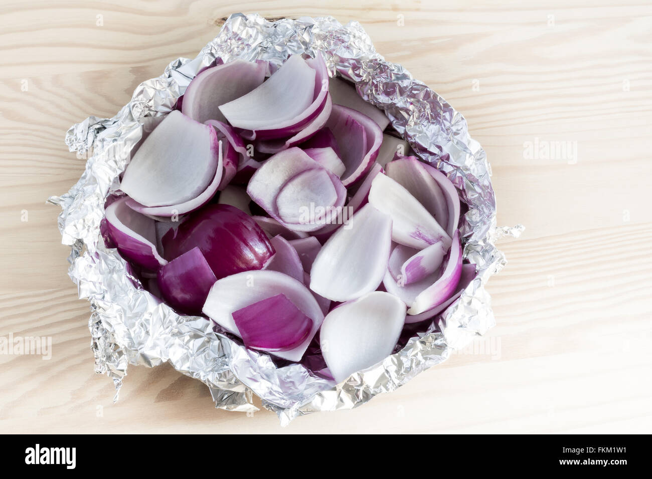 Fresh peeled and chopped red onion slices in tin foil Stock Photo
