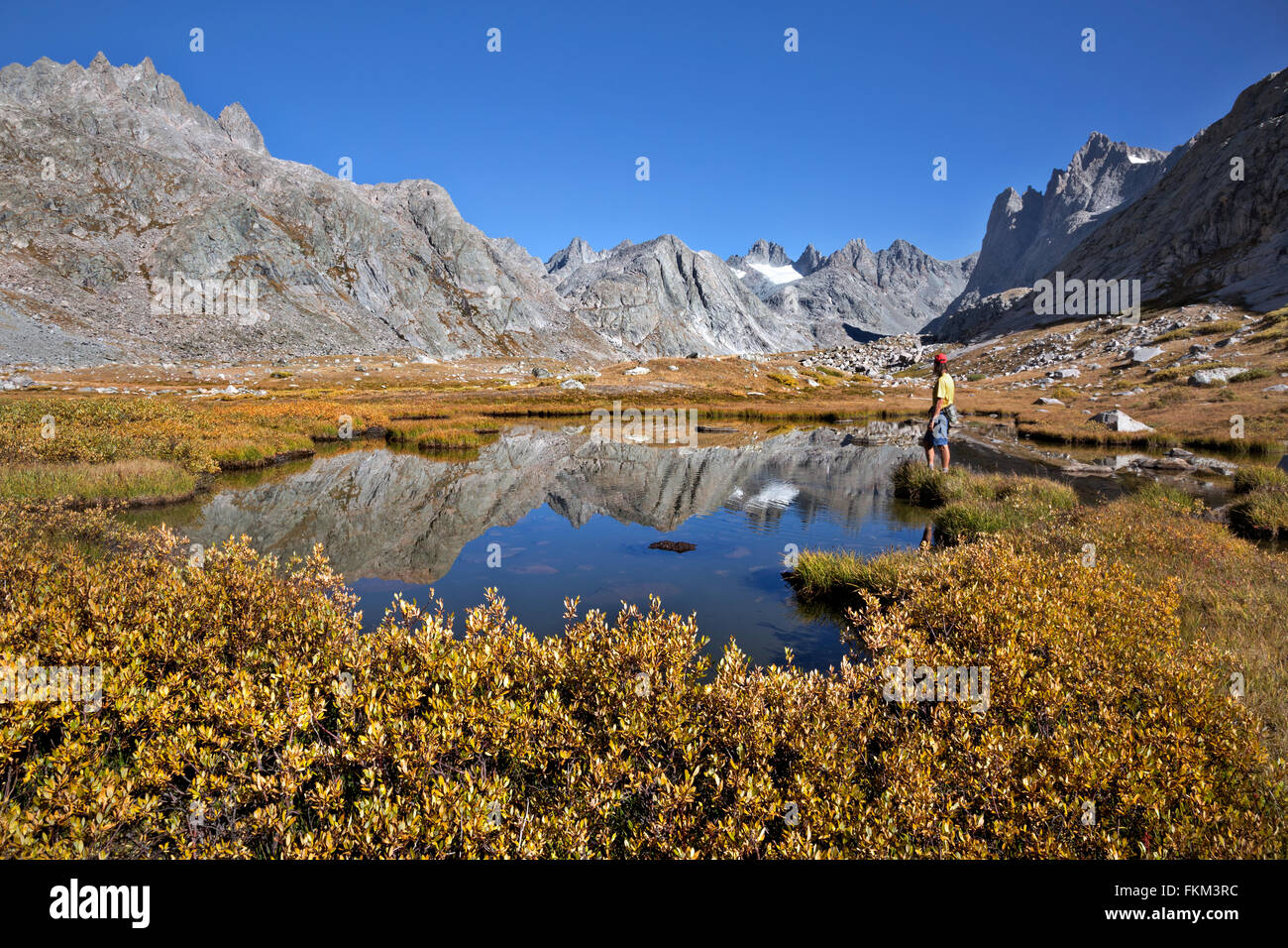 WY01248-00...WYOMING - Hiker at a small tarn near Upper Titcomb Lake in the Titcomb Basin area of the Wind River Range . Stock Photo