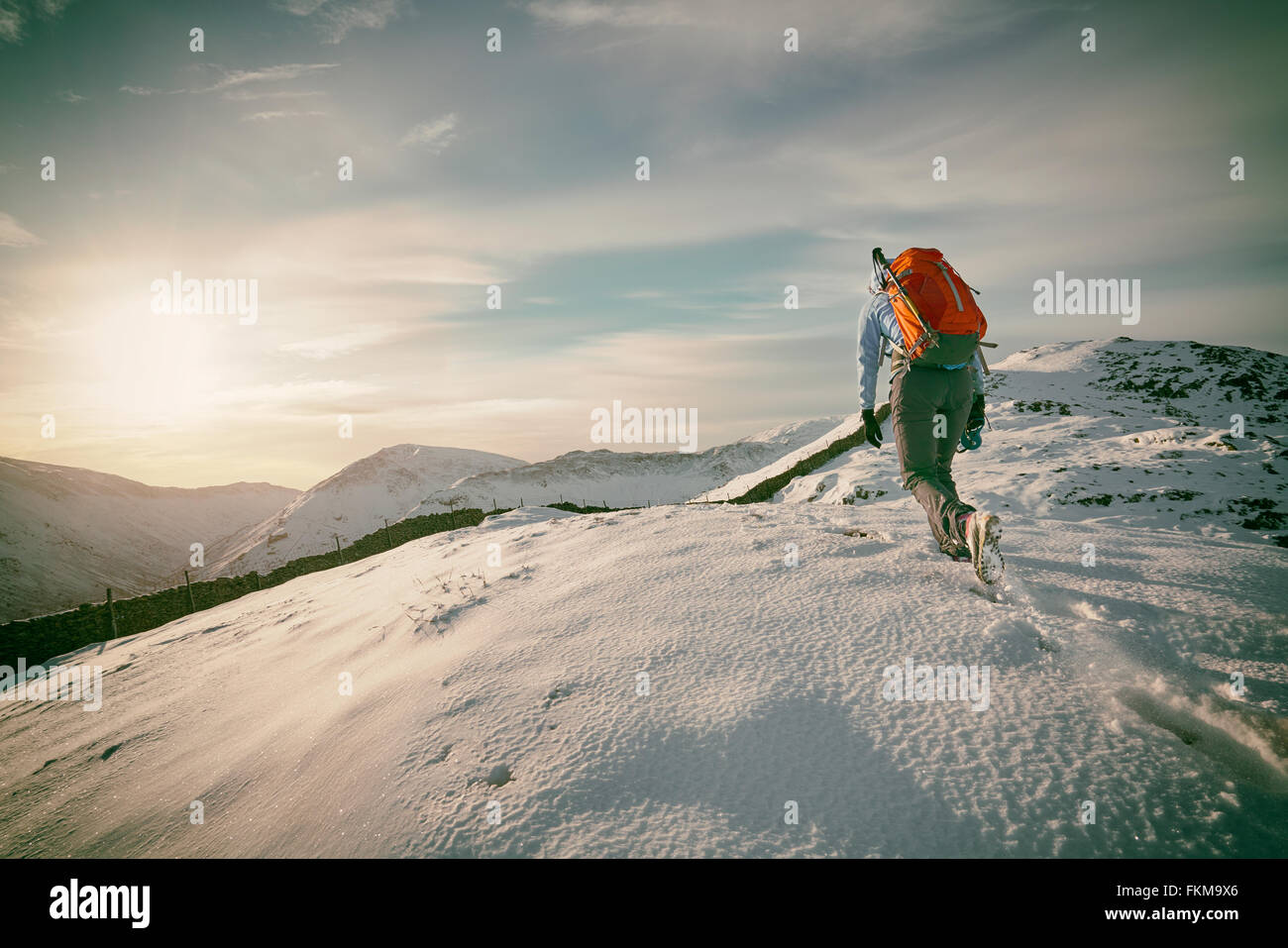 Hiker walking over snow covered mountains in the UK. Grain and colour styling applied Stock Photo