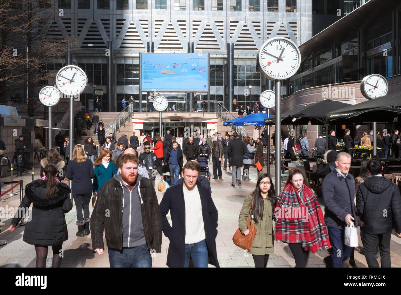 People walking through the clocks, Canary Wharf London UK Stock Photo