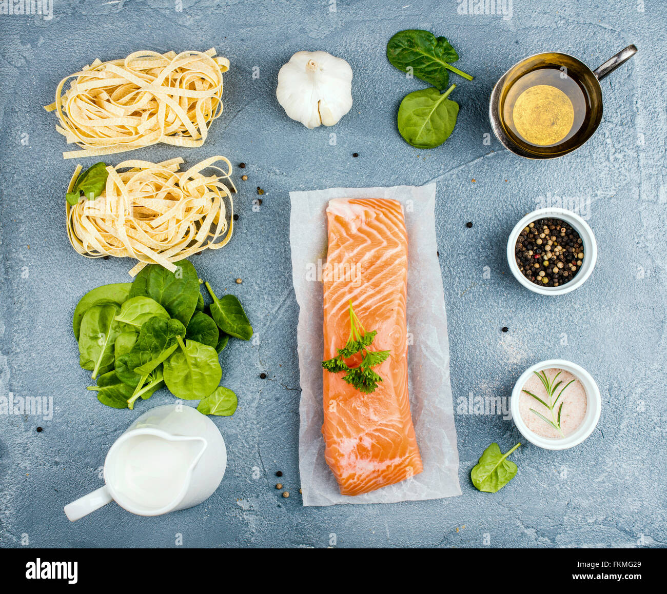 Ingredients for cooking pasta tagliatelle with salmon, spinach and cream on grey concrete textured background, top view Stock Photo
