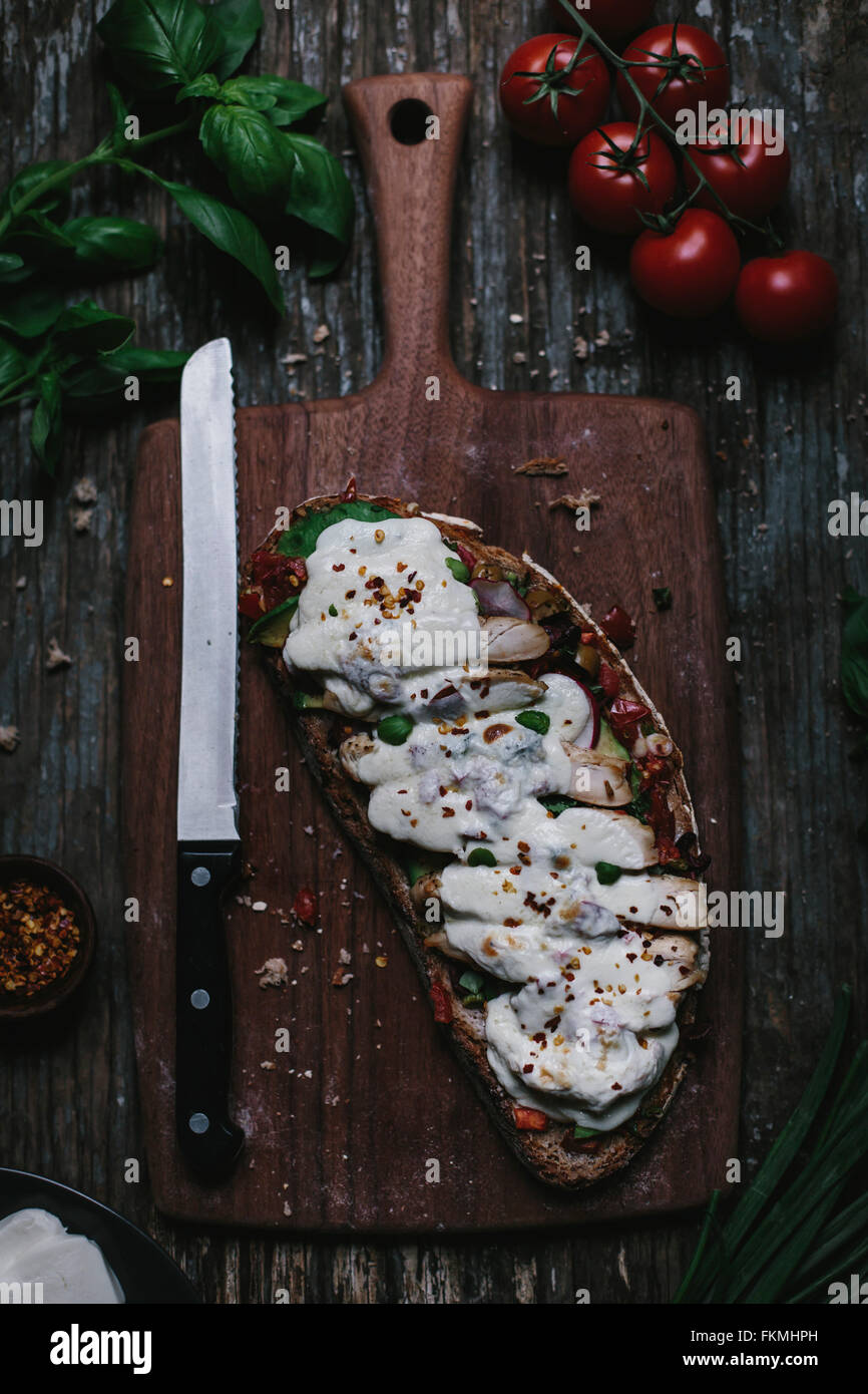 An open-face chicken caprese sandwich covered with melted mozzarella cheese  is photographed from the top. Stock Photo