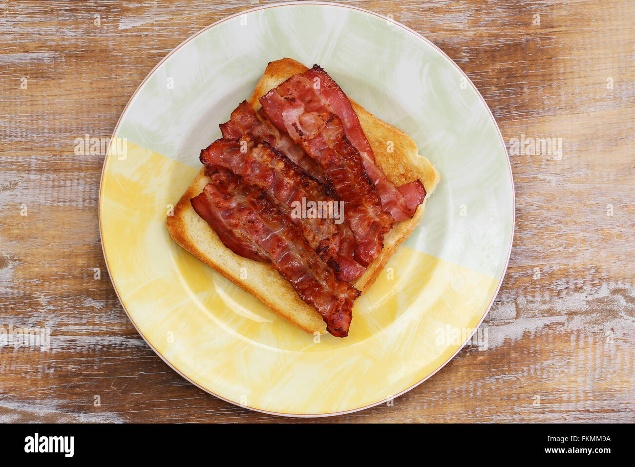 Toast with crispy bacon on plate on rustic wooden surface Stock Photo