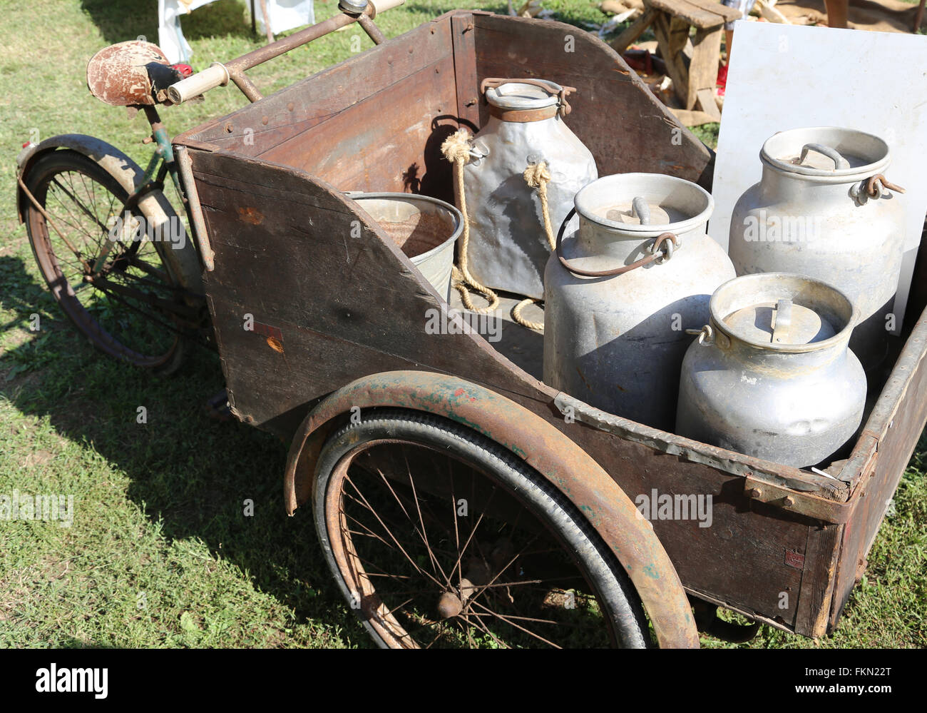 ancient big bicycle with cart with three wheels for transporting milk cans Stock Photo