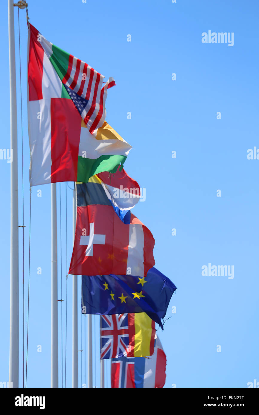 many flags of many nations in the wind on a sunny day with blue sky Stock Photo