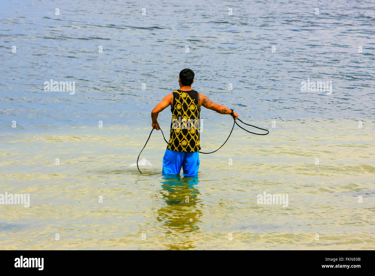 A Silhouette of a Man Throwing a Cast Net for Bait Fish with the
