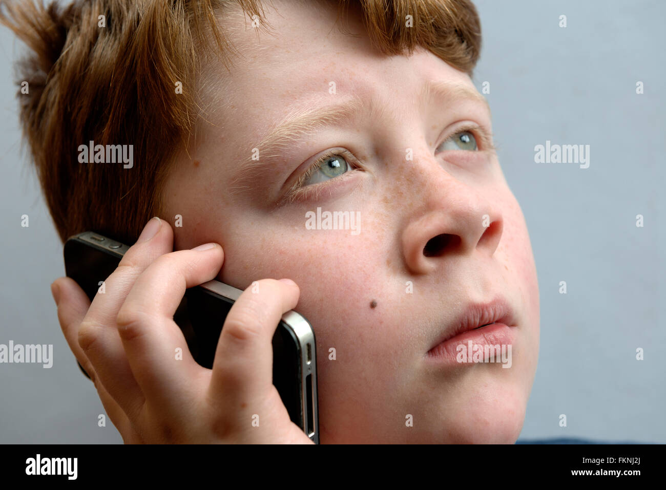 Worried looking boy taking on mobile phone Stock Photo