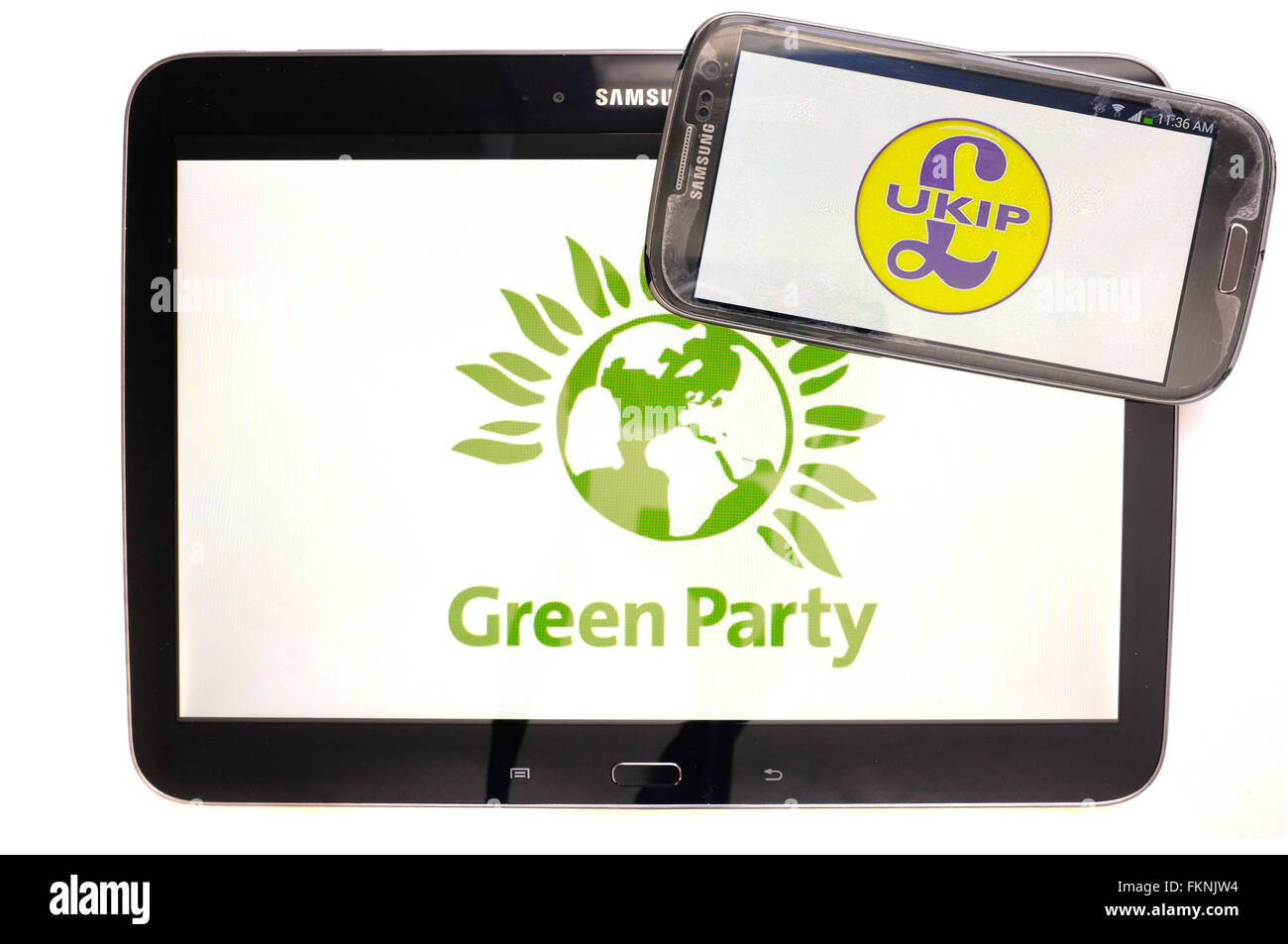 The Green Party and UKIP logos displayed on the screens of a tablet and a smartphone against a white background. Stock Photo