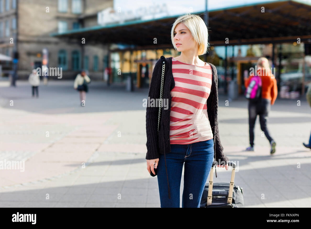 Young woman traveling with a wheeled suitcase Stock Photo