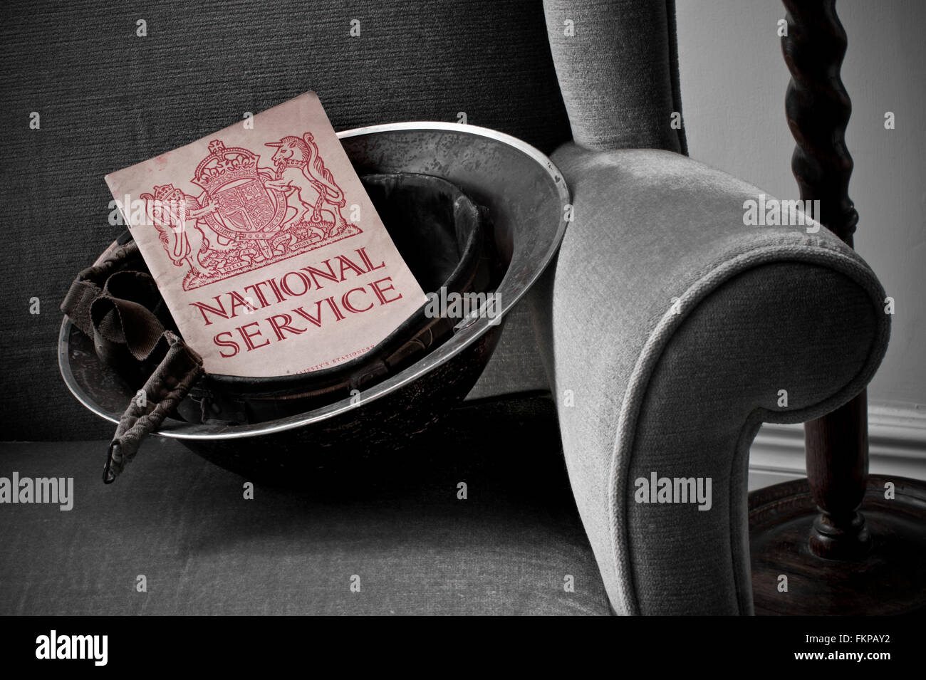 NATIONAL SERVICE UK WW2 military helmet on period chair with 1939 National Service 'call to arms' booklet, for volunteer sign up to wartime duties Stock Photo