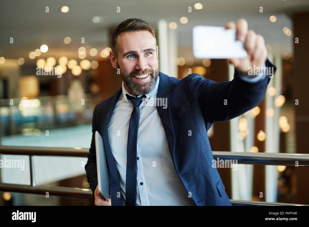 Businessman in black suit using a mobile phone for a video call with partners Stock Photo