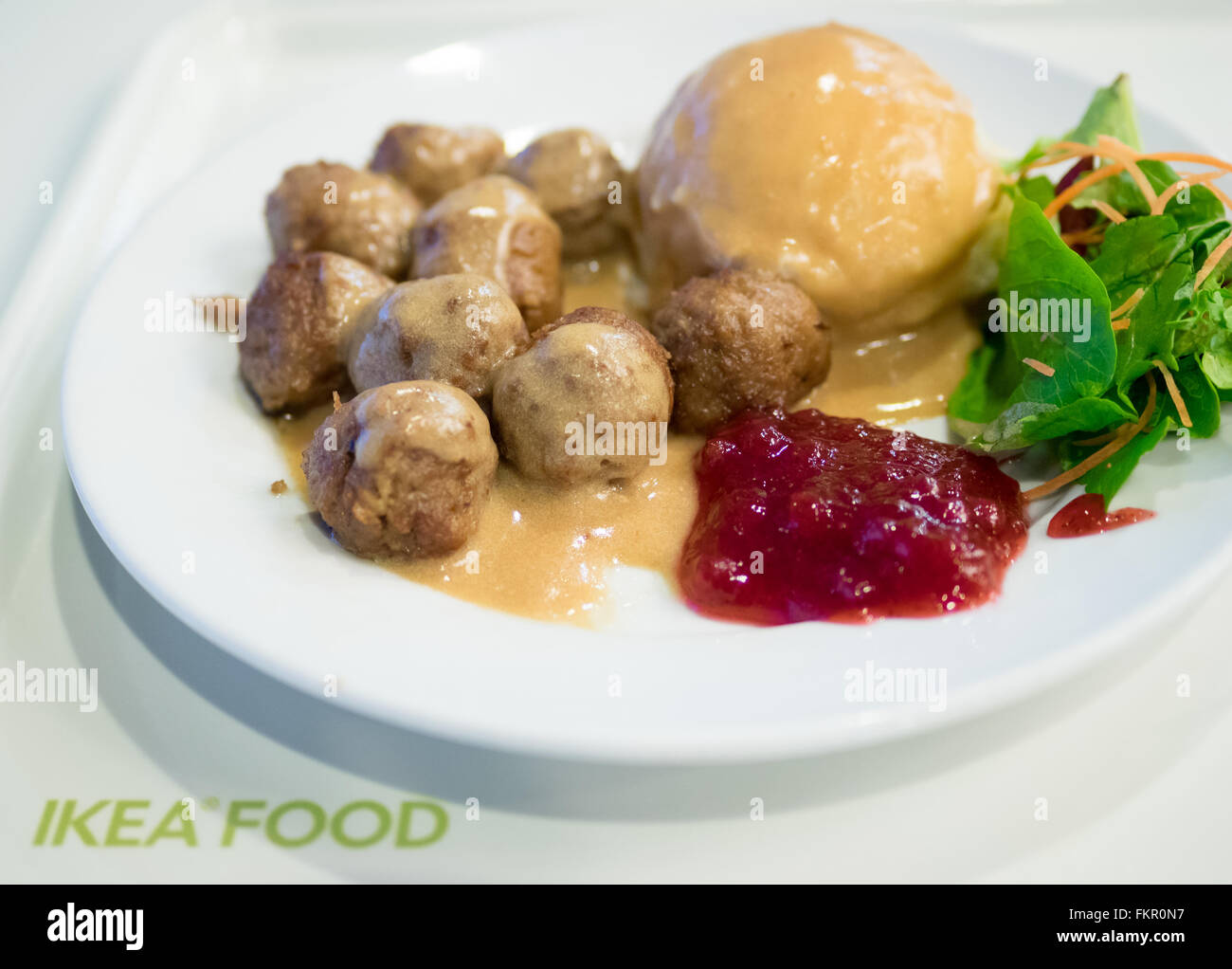 A plate of IKEA meatballs, mashed potatoes, cream gravy, green salad and lingonberry sauce. Stock Photo