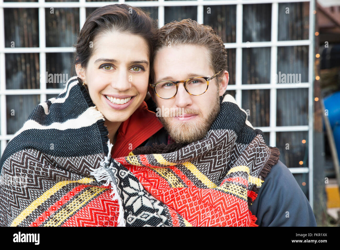 Couple wrapped in blanket outdoors Stock Photo