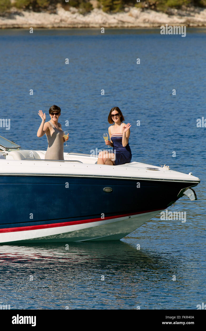 Women waving from boat in ocean Stock Photo