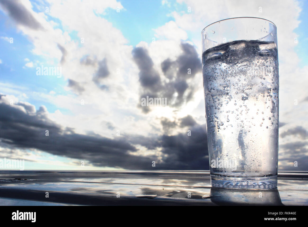 Ice cold glass of water with dramatic cloudy sunset Stock Photo - Alamy